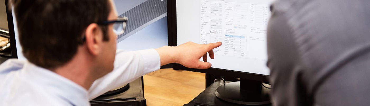 mark williams technical services manager at klinger united kingdom showing software to colleague on a computer screen