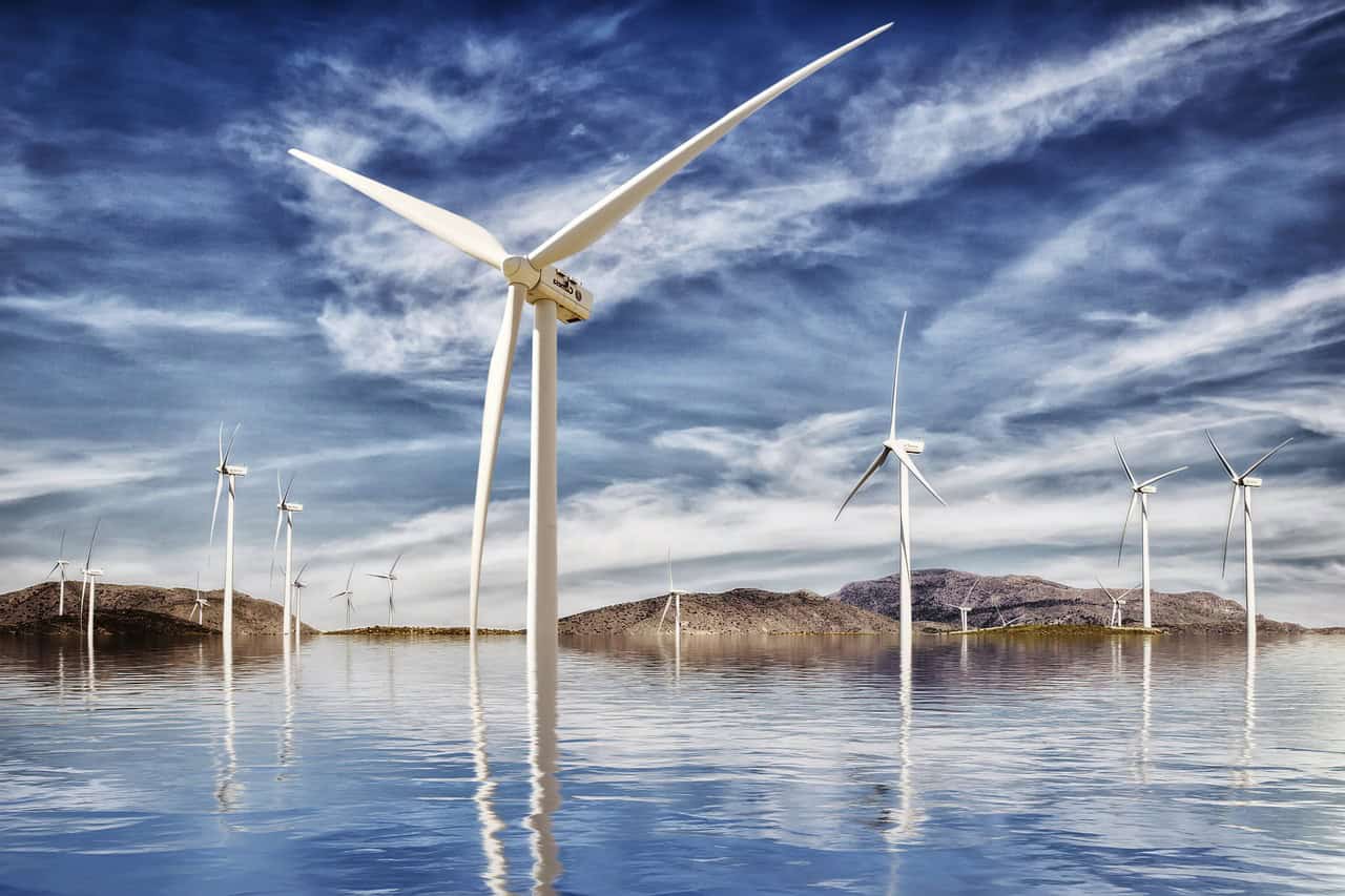 wind turbines dispersed around water with small hills in background