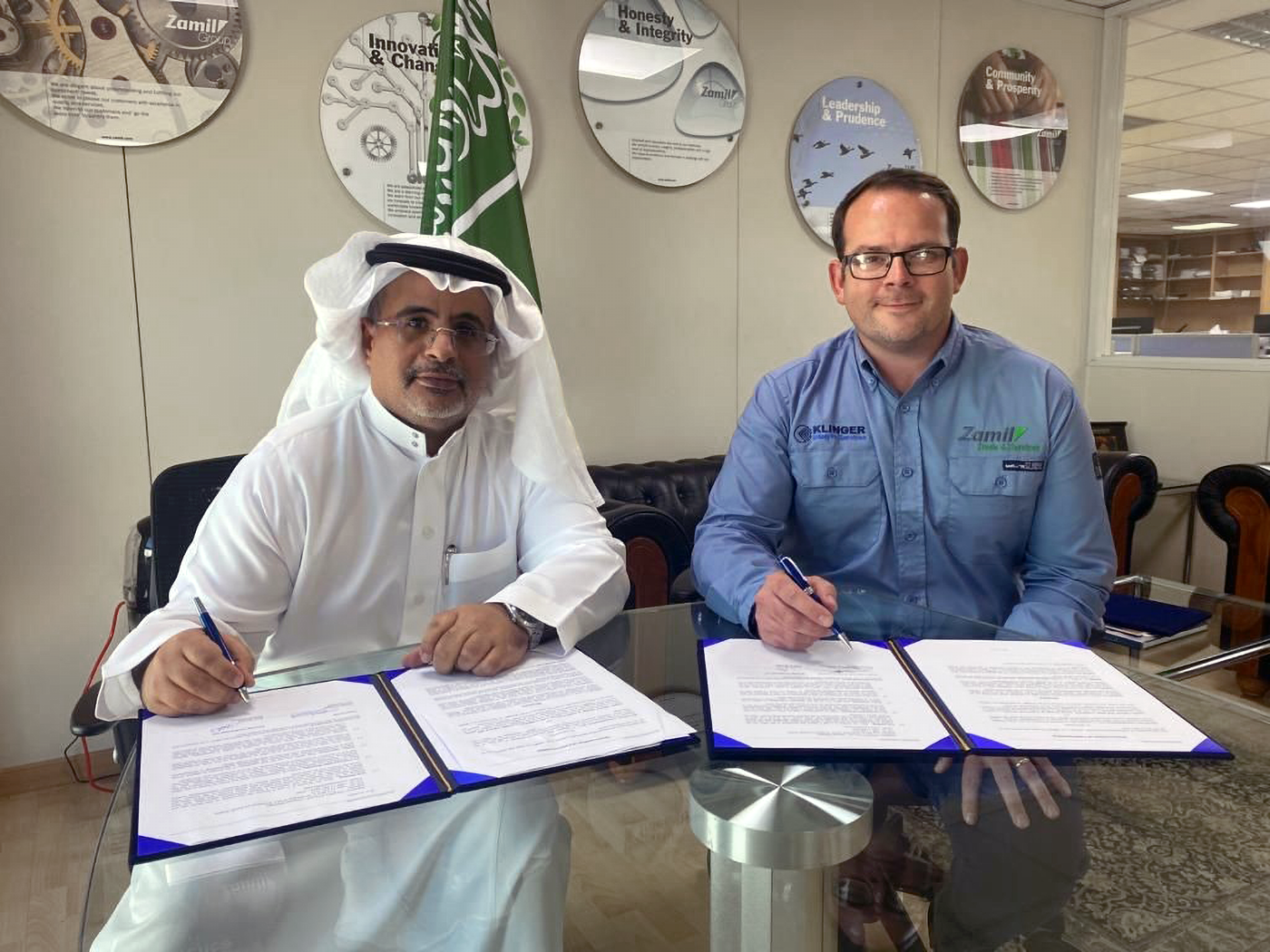zamil representative on the left signing a document with Matt Hayllar, Country Manager at KLINGER UK