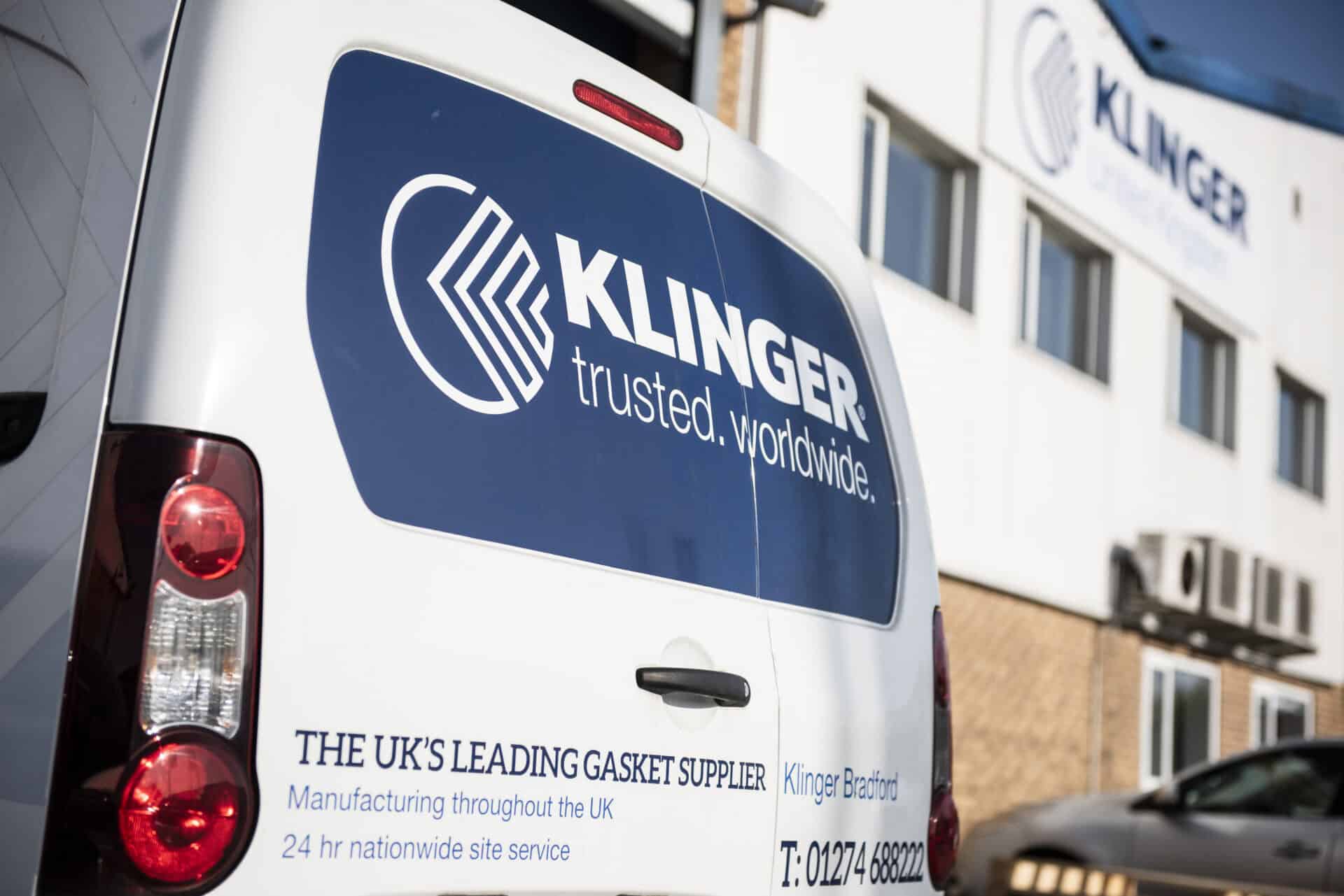 KLINGER UK van with trusted.worldwide. logo displayed on it. In the distance stands the Bradford headquarters with the KLINGER United Kingdom logo blurred out.